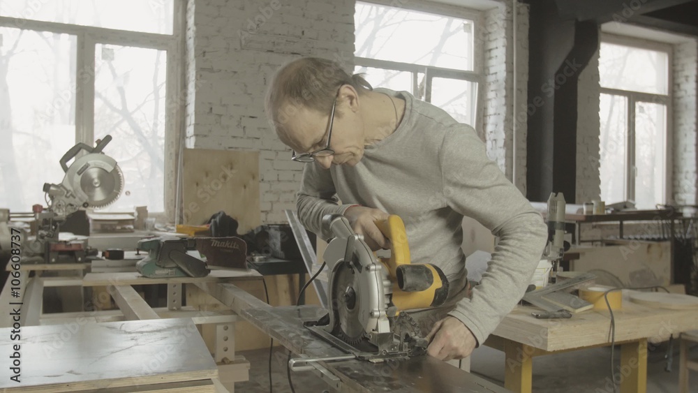 Professional carpenter fixing circular saw on of wooden board on working table. Making furniture. Manufacturer. Professional carpenter fixing circular saw on of wooden board on working table. Making furniture. Manufacturer.