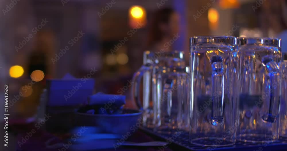 Close-up shot of clean glassware on the bar counter with customers and waiters walking in cafe Close-up shot of clean glassware on the bar counter with customers and waiters walking in cafe