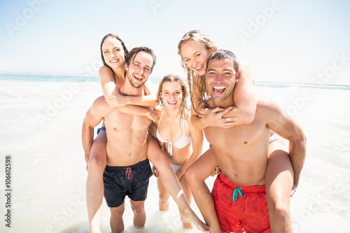 Men giving a piggy back to women on the beach