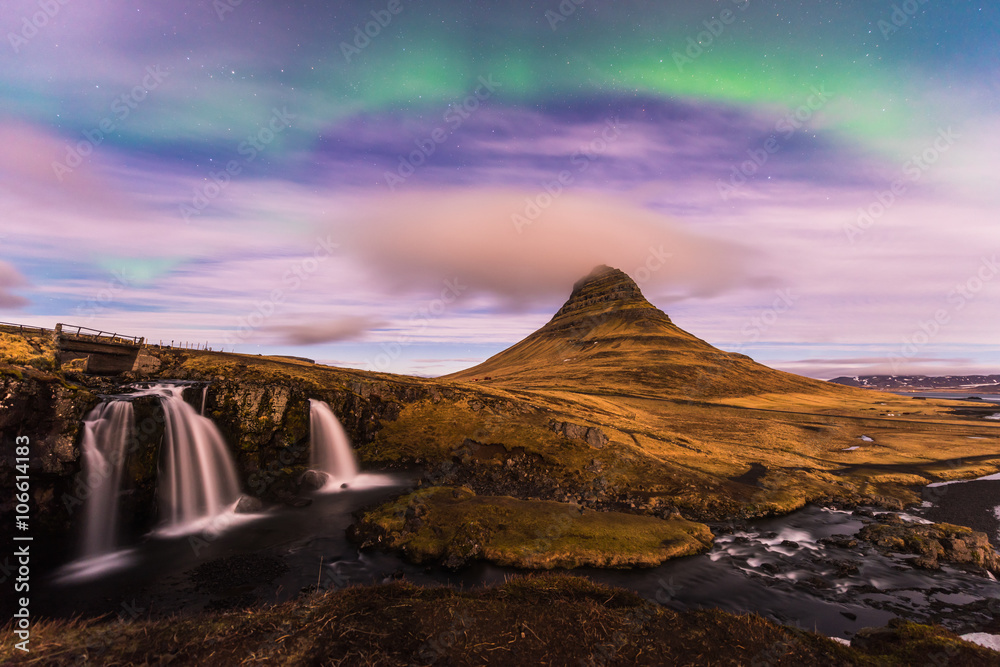 Northern Light over Kirkjufell, Grundarfjordur town, West Iceland with small dark cloud cover the mountain