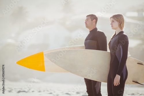 Couple with surfboards standing on beach