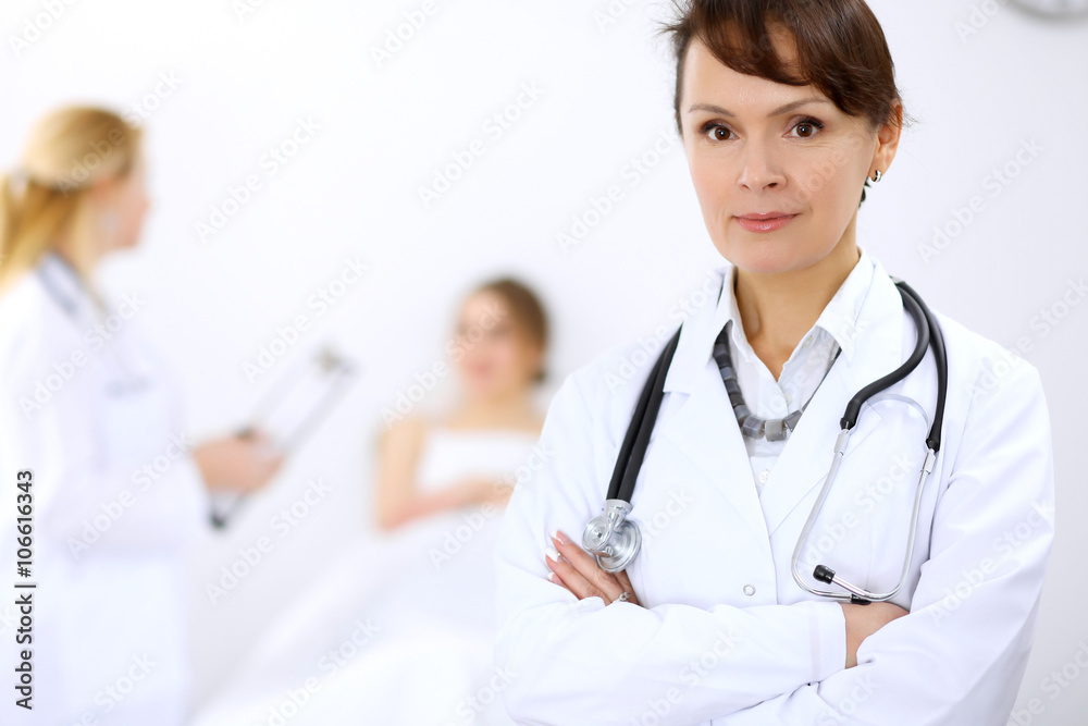 Female doctor smiling on the background with patient and his doctor Female doctor smiling on the background with patient and his doctor