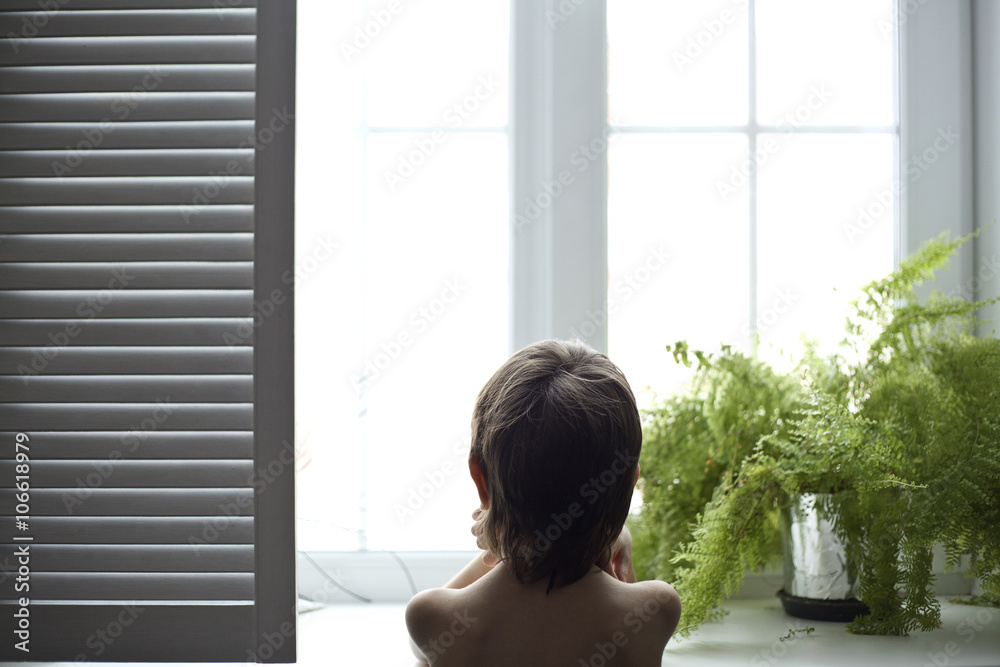 Asian boy looking out bedroom window Asian boy looking out bedroom window