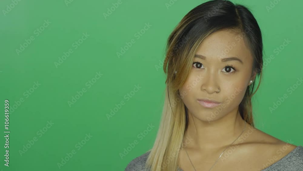 Cute Asian girl glaring, on a green screen studio background Cute Asian girl glaring, on a green screen studio background
