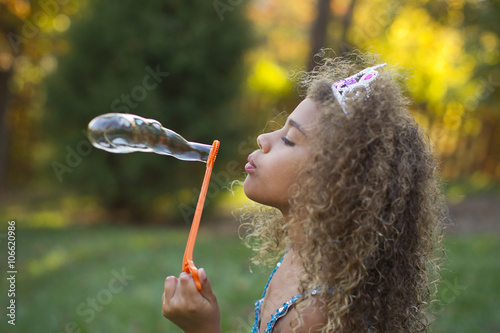 Mixed race girl blowing bubbles outdoors photo