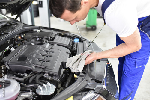 Schilderij op canvas Mechaniker kontrolliert Ölstand vom Motor eines autos in der Werkstatt // profes