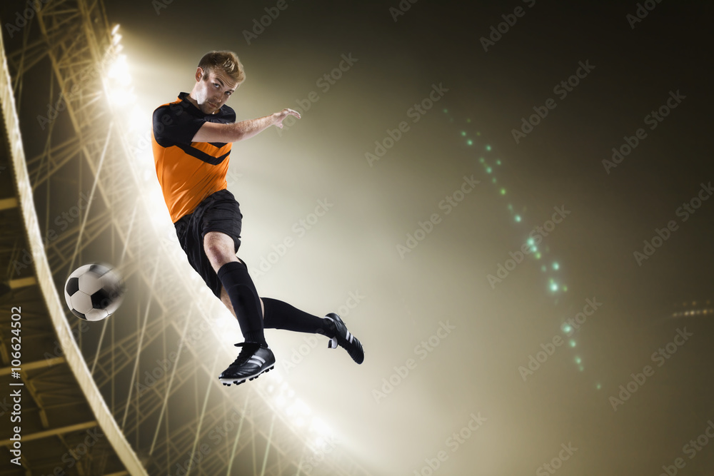 Athlete kicking soccer ball in stadium