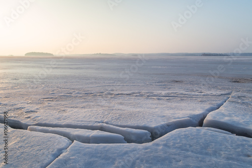 Fototapeta Naklejka Na Ścianę i Meble -  Cracked ice at a frozen lake in Finland in the morning. Copy space.