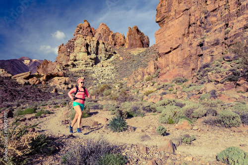 Woman trail ultra running in mountains with backpack