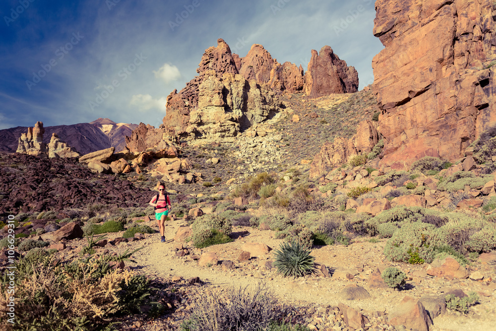 Fototapeta premium Young woman trail running in mountains on summer day