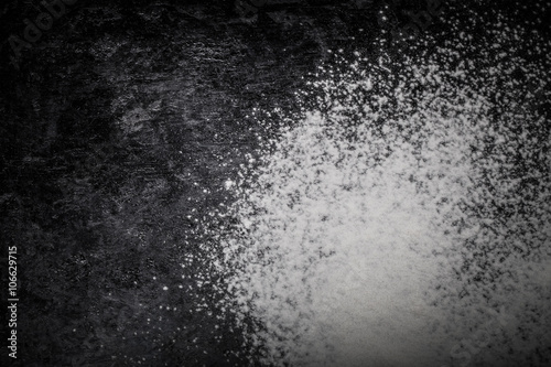 Flour spilling on black background. Toned