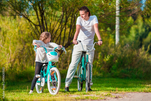 Young father and little girl biking at summer warm day