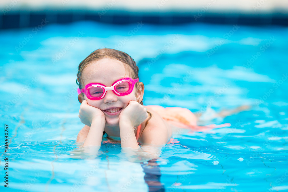 Little happy adorable girl in outdoor swimming pool