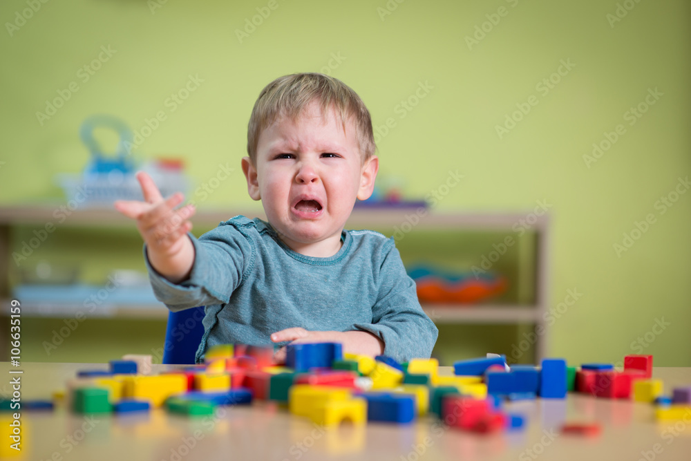 Tearful boy in nursery with toys