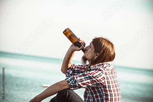 Photography Man depressed with wine bottle sitting on beach outdoor