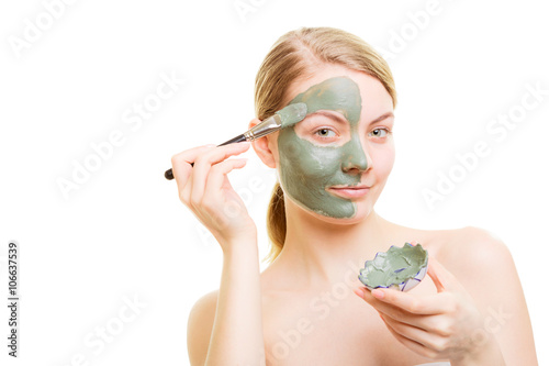 Girl applying facial clay mask to her face