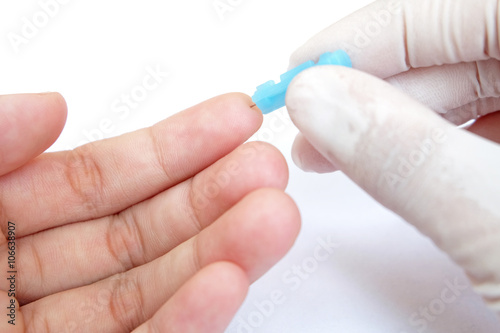 blue blood lancet penetrates to the skin of left hand with white