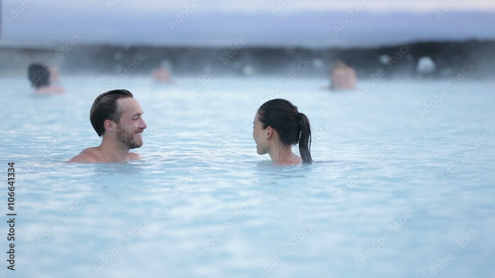 Hot spring geothermal spa on Iceland. Romantic couple in love relaxing in hot pool on Iceland. Young woman and man enjoying bathing relaxed in a blue water lagoon Icelandic tourist attraction. Sunset.