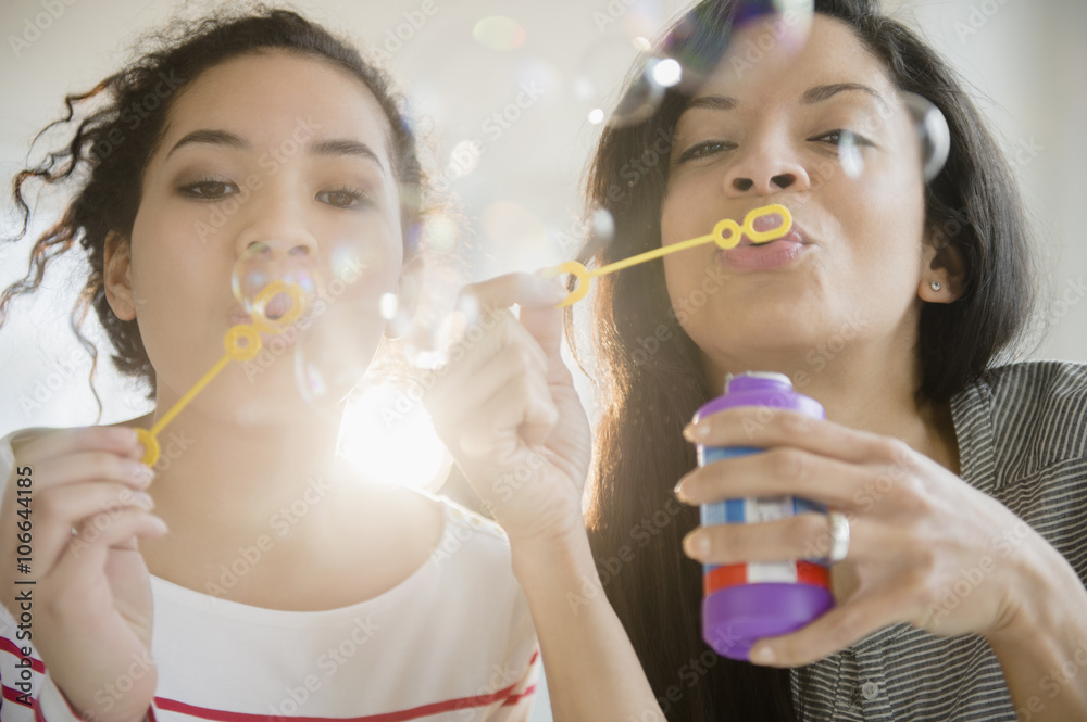 Mother and daughter blowing bubbles together Mother and daughter blowing bubbles together