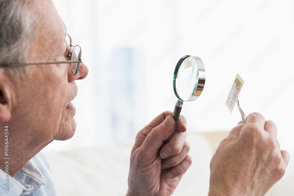 Senior Caucasian man examining stamp with magnifying glass Senior Caucasian man examining stamp with magnifying glass