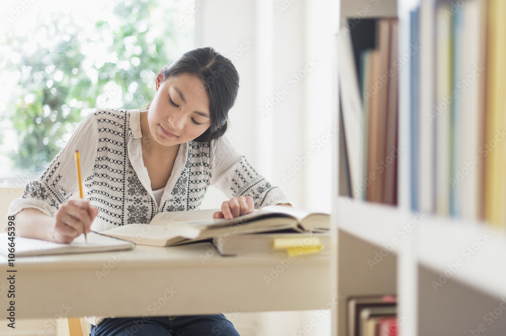 Mixed race teenage girl studying in library