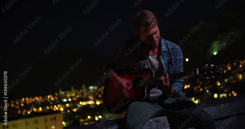 Happy teen guitarist playing outside on a rooftop Happy teen guitarist playing outside on a rooftop