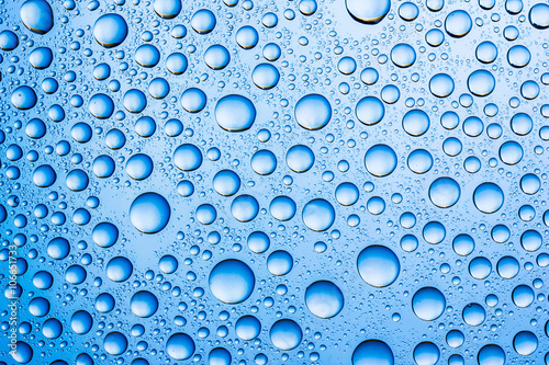 Blue water drops on glass surface texture.