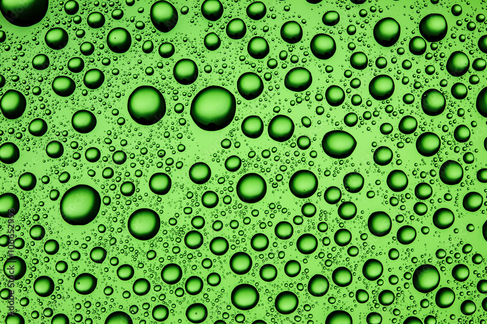 Water drops on transparent glass green background.