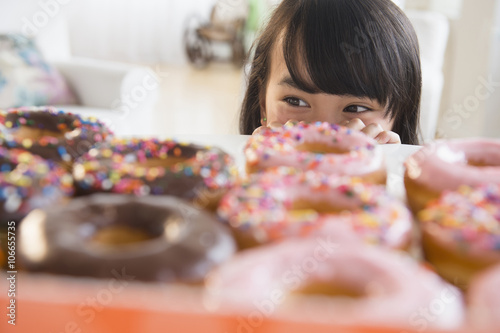 Filipino girl peering at donuts on table