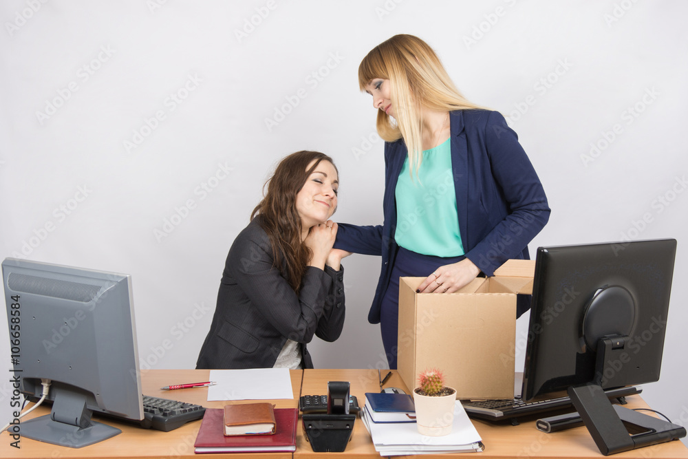 The girl in the office is facing the box with things and says goodbye to a colleague The girl in the office is facing the box with things and says goodbye to a colleague