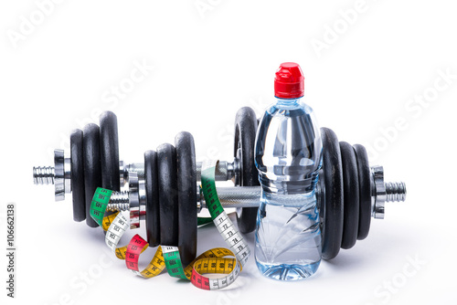 Dumbbells with measuring tape and bottle of water on white