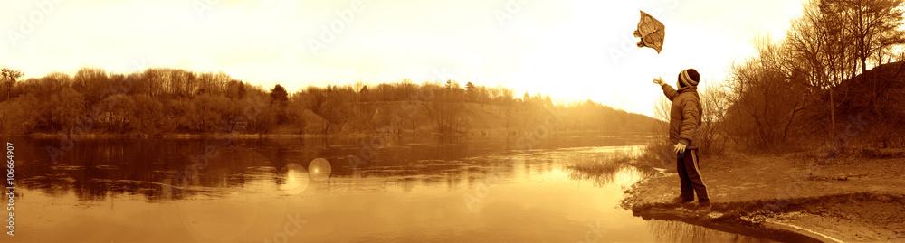 Fototapeta premium boy with a kite on the banks of the river in autumn