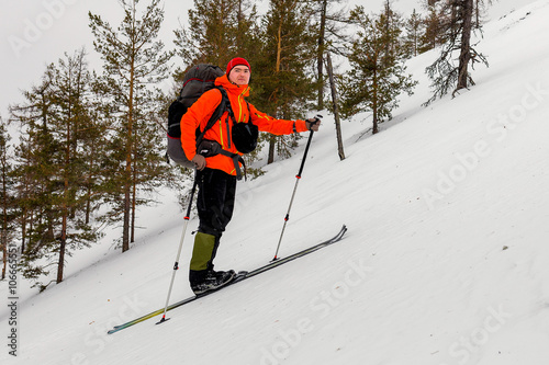 Skier Mountain hiker climbs at a very steep hill, with a heavy b