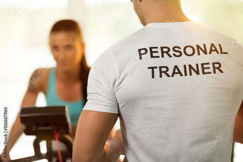 Obraz na plátně Personal trainer with woman on cycling machine at the gym