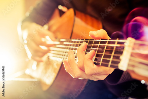 Fotografia, Obraz the young guy playing an acoustic guitar. Shooting backlit