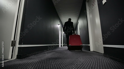 Businessman with a suitcase in a corridor of hotel