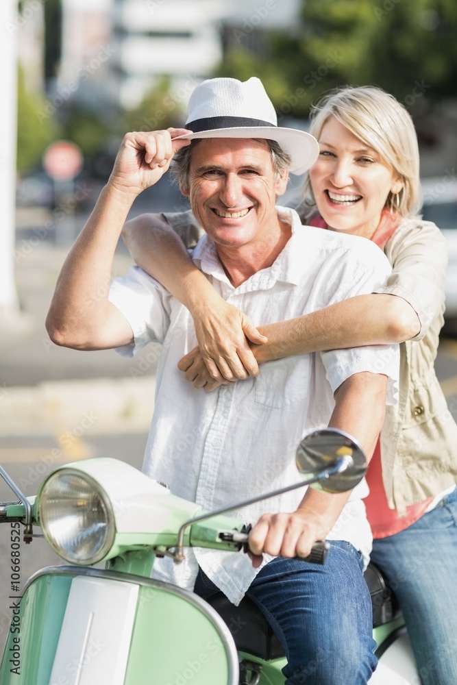 Smiling couple sitting motor scooter