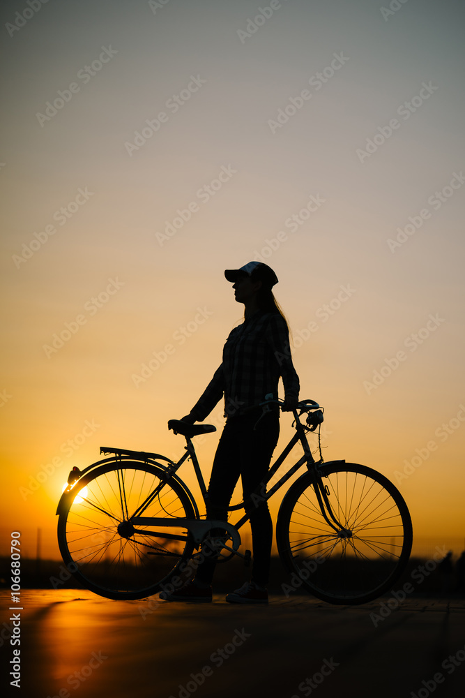 Obraz premium beautiful hipster girl with a bicycle on the road during sunset