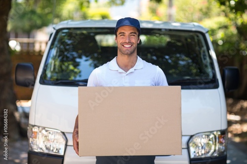 Portrait of smiling delivery person holding cardboard box 