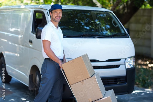 Portrait of smiling delivery man carrying cardboard boxes 