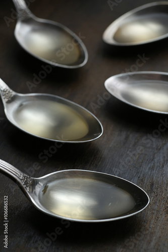 Olive oil in the spoons on wooden background. Close up