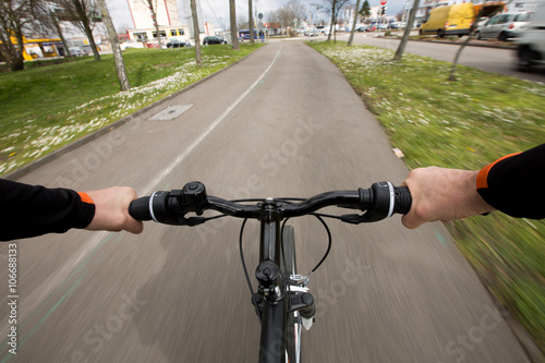 Close-up image of cyclist man hands on handlebar riding bike in park, face is not visible.Young man riding bike in city park .View from bikers eyes.