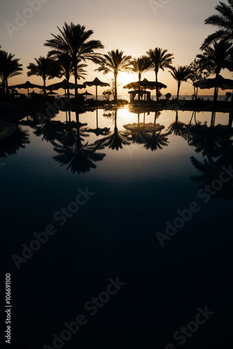 Beautiful sunset at a beach resort in tropics with palms and wat