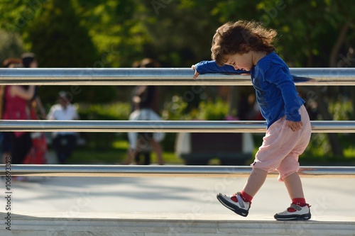 Obraz na plátne Young girl walking on wall holding metal railings