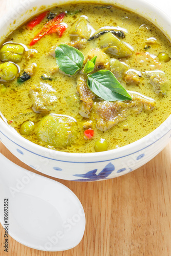 green curry and white spoon on wood background.