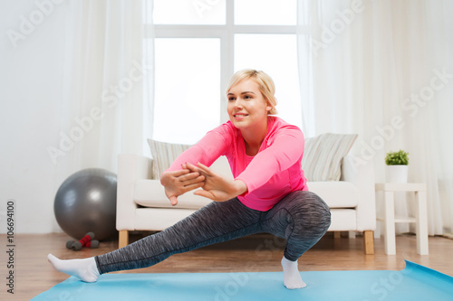 happy woman stretching leg on mat at home