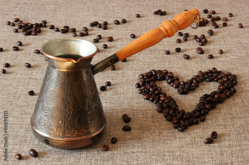 Coffee Turk and coffee beans in the shape of a heart on sack cloth background.