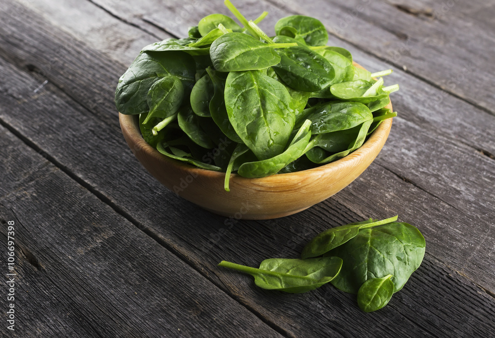 Spinach leaves in bowl on dark wooden background Spinach leaves in bowl on dark wooden background