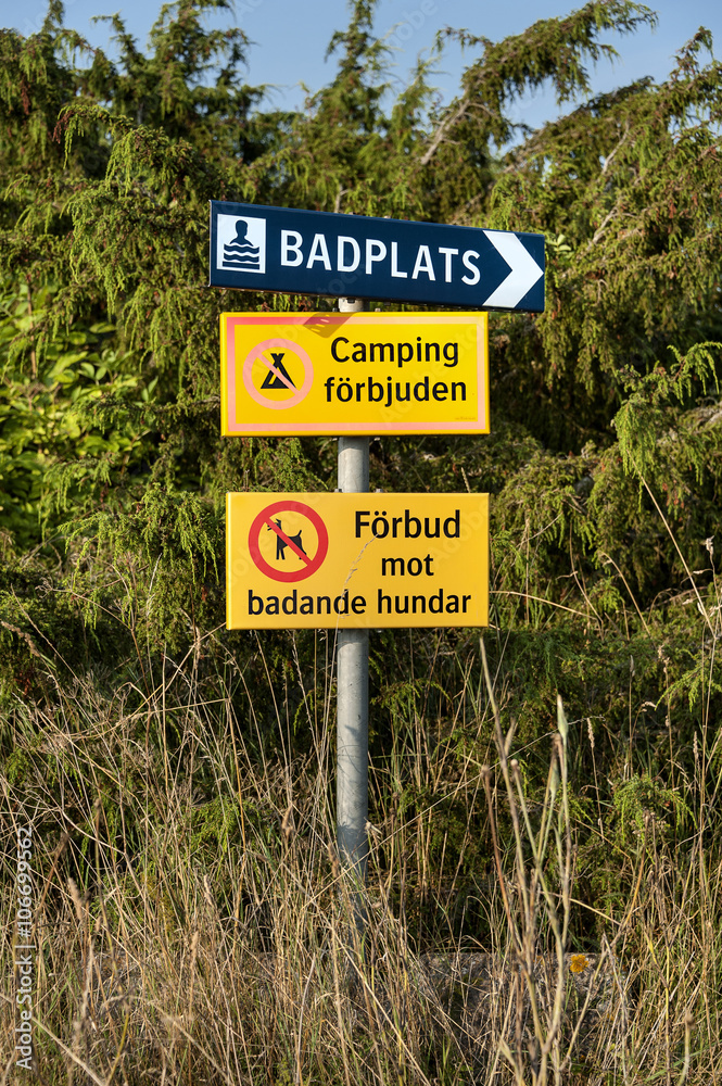 Swedish signs which indicate the direction to a baseplate, that camping is not allowed and dogs are not allowed to have a swim