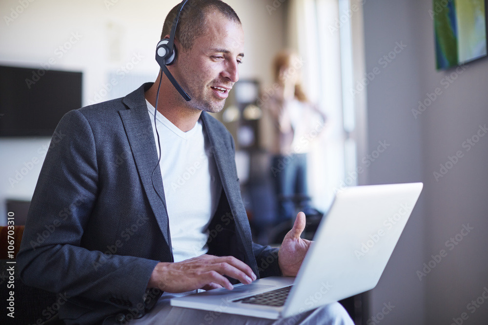 Businessman with headset using laptop in hotel room Businessman with headset using laptop in hotel room